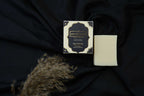 AMI NATURAL BLACK OUDH SOAP with elegant black and gold packaging alongside a plain off-white soap bar on black fabric