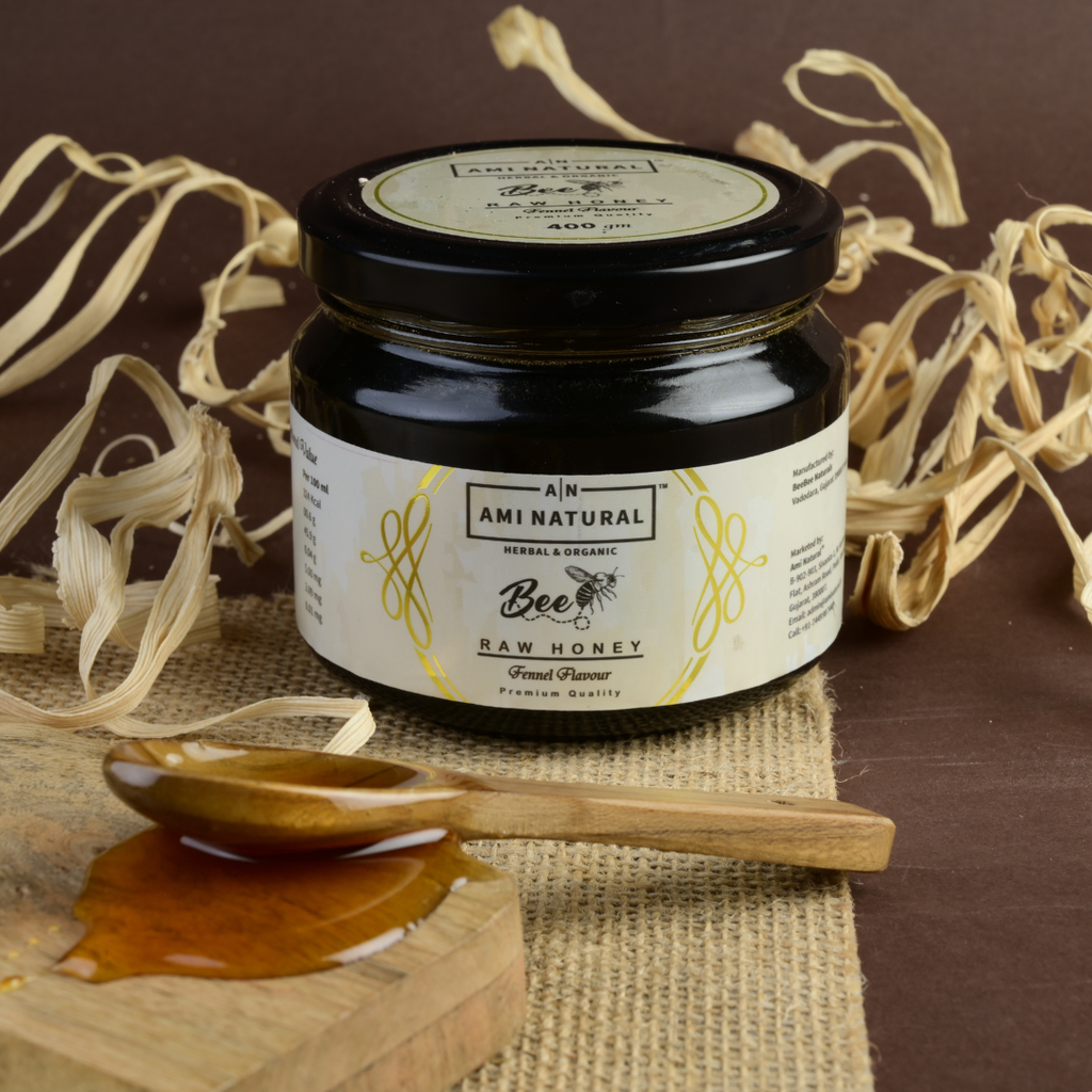 Ami Natural Raw Fennel Honey in a dark glass jar with a black lid, white label featuring herbal design, next to wooden spoon and honey drizzle